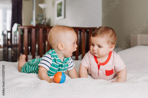 Obraz na płótnie Group portrait of two white Caucasian cute adorable funny baby boys lying together on bed communicating and playing