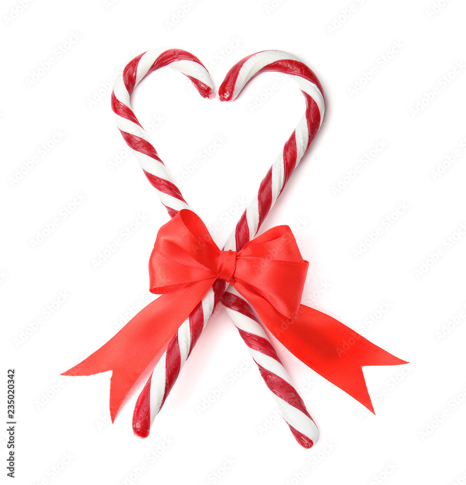 Heart shape made of tasty candy canes with bow on white background