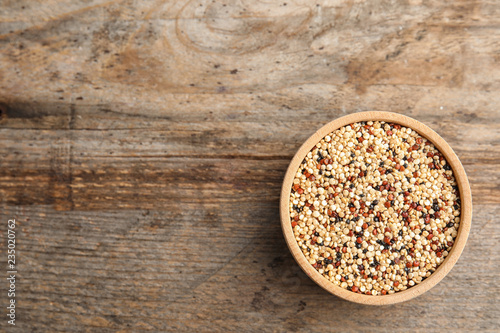 Bowl with mixed quinoa seeds and space for text on wooden background, top view