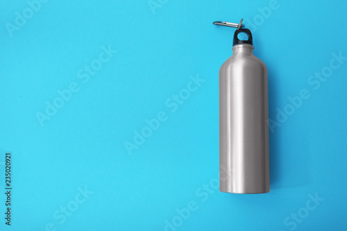 Sport bottle with space for text on color background, top view