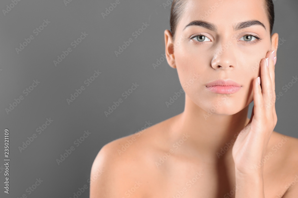 Portrait of beautiful young woman and space for text on grey background. Cosmetic surgery concept