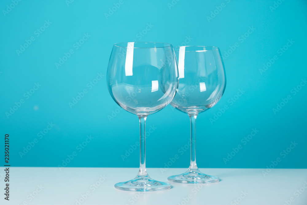 Clean wine glasses on table against color background Clean wine glasses on table against color background