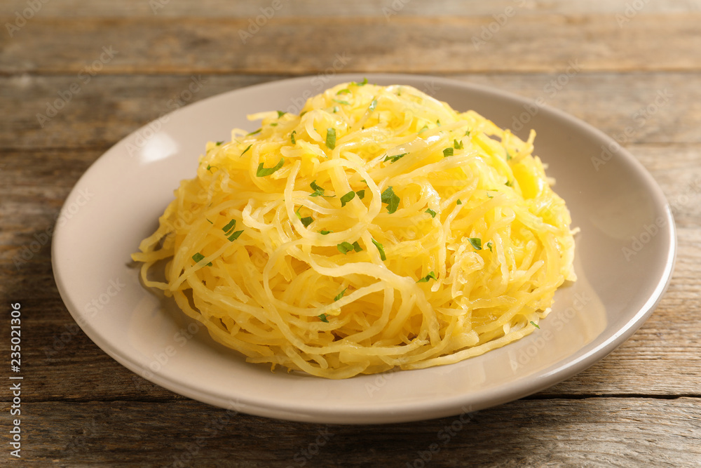 Plate with cooked spaghetti squash on wooden table Plate with cooked spaghetti squash on wooden table
