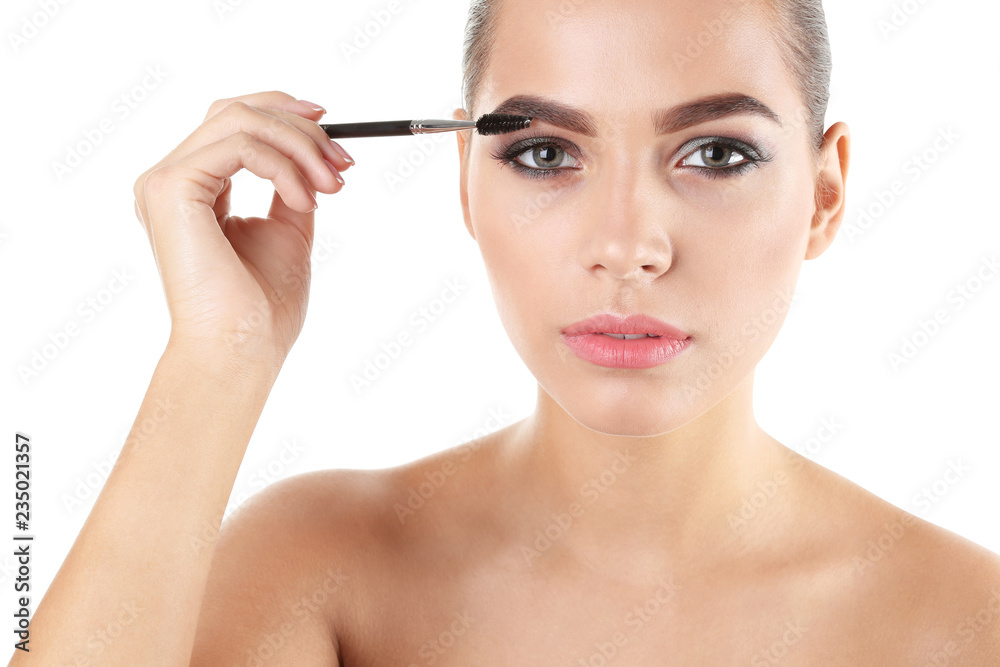 Portrait of beautiful woman applying stylish makeup with brush on white background