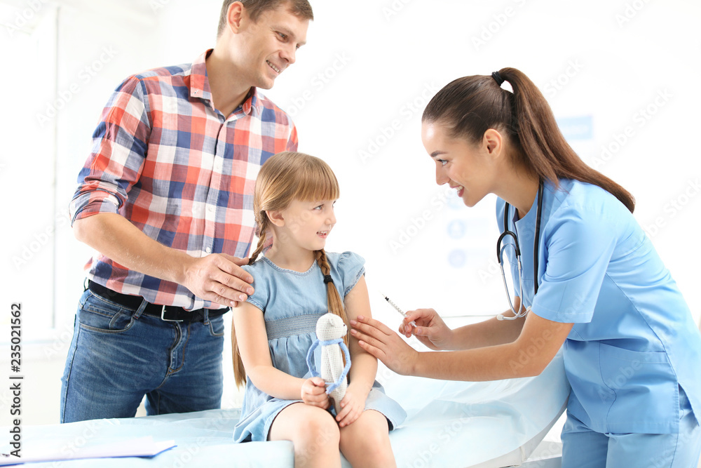 Children's doctor vaccinating little girl near parent in hospital Children's doctor vaccinating little girl near parent in hospital