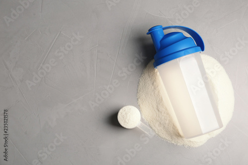 Bottle, protein powder and space for text on grey background, top view. Preparing shake