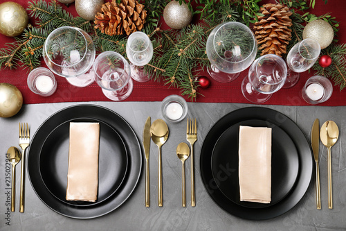 Christmas table setting with plates, cutlery, napkins and festive decor on grey background, flat lay
