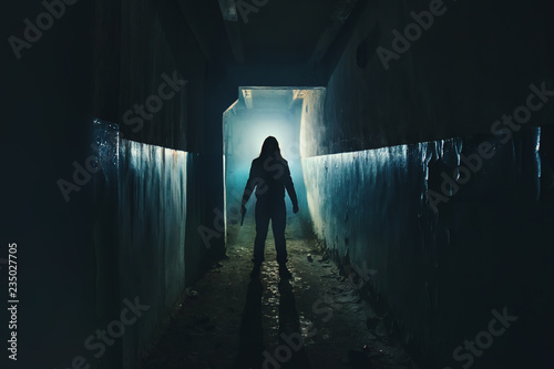 Silhouette of man maniac or killer or horror murderer with knife in hand in dark creepy and spooky corridor. Criminal robber or rapist concept in thriller atmosphere