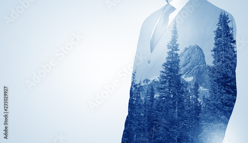 Young businessman standing and meditate with trees on the background 