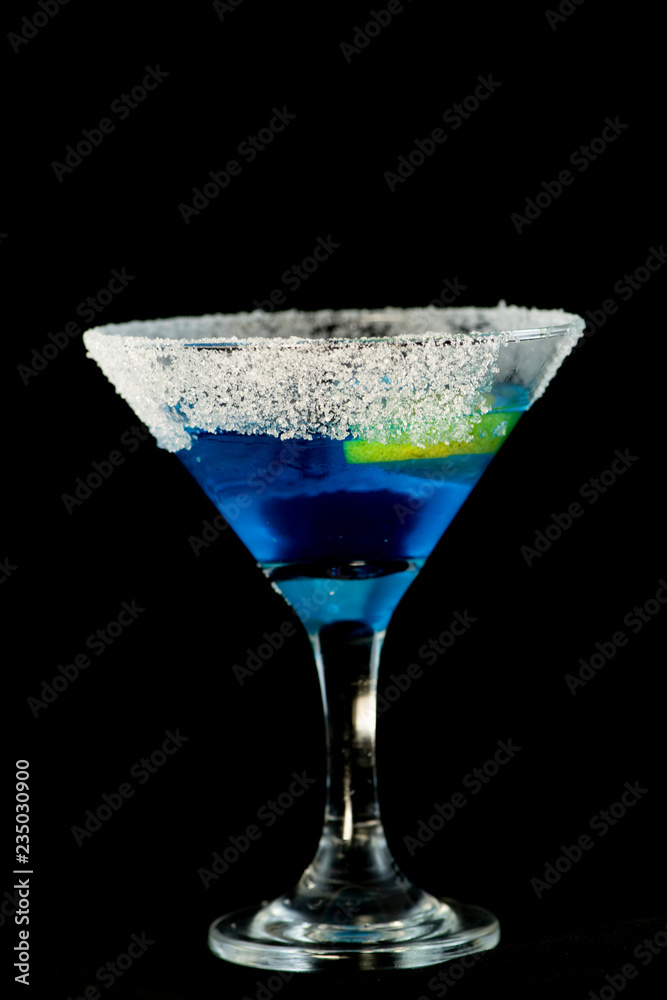Blue kamikaze cocktail with vodka, lime juice, blue curacao, sugar and lime wedge