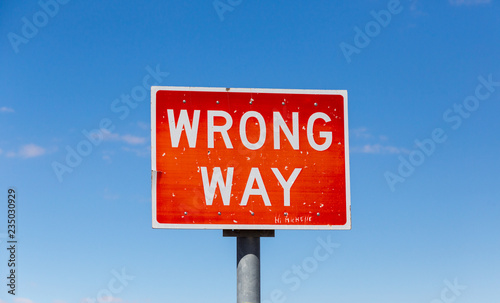 Wrong way road sign isolated against sky