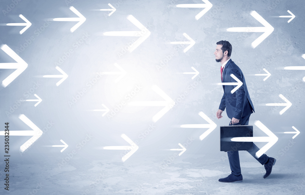 Obraz premium Businessman walking with arrows on the background and briefcase on his hand 