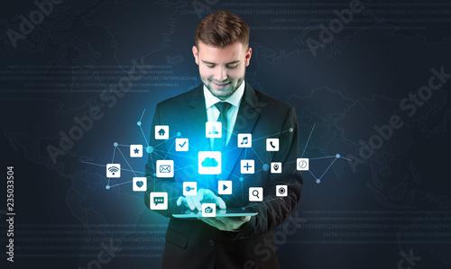 Handsome businessman in suit with tablet on his hand and application icons above 