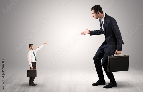 Small businessman in shirt pointing to an afraid businessman 