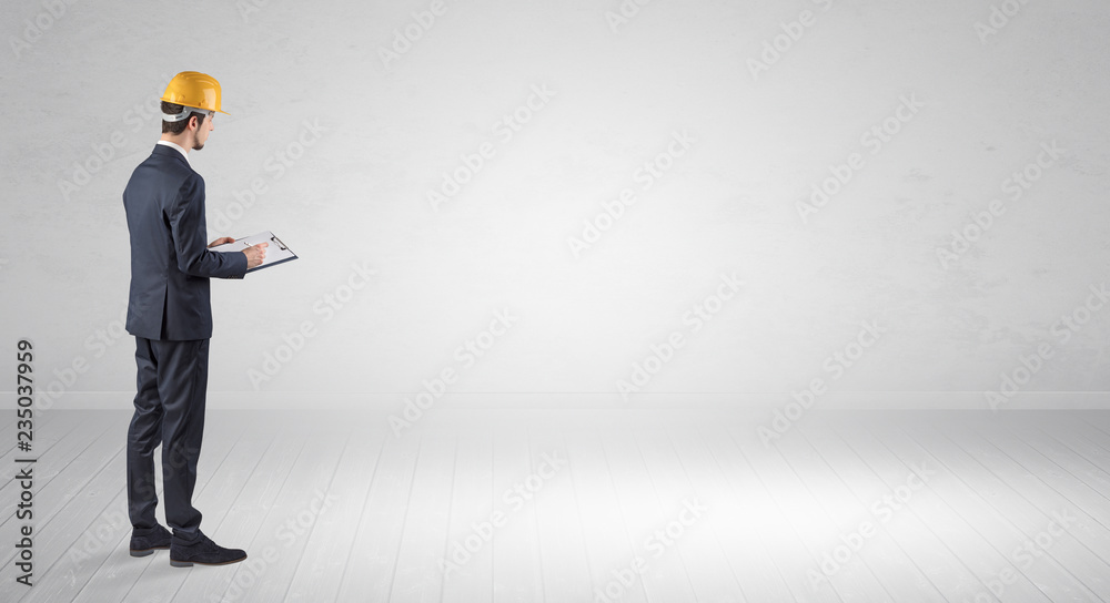 Young architect with construction helmet standing in an empty space and holding a plan
Young architect with construction helmet standing in an empty space and holding a plan
