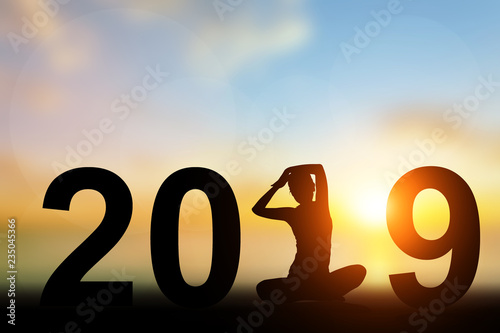 Abstract blur nature backSilhouette Asia woman yoga in 2019 text on the beach at sunset. Happy new yearground