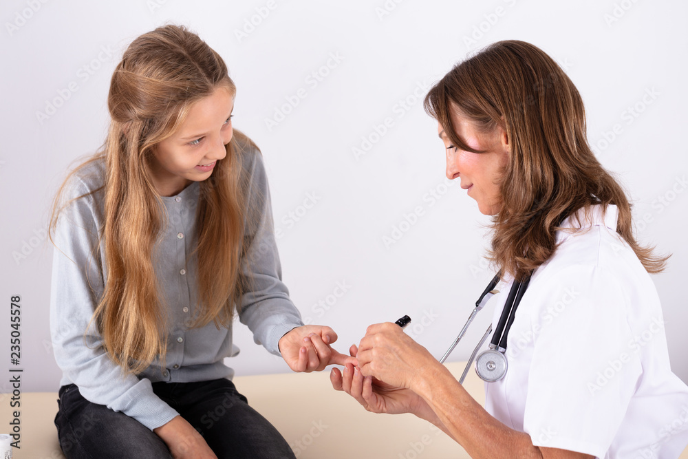 Fototapeta premium Doctor Checking Girl's Blood Sugar Level With Glucometer