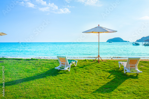 Beach chairs and beach umbrellas are on the lawn at the beach.Sea view and bright sky. photo