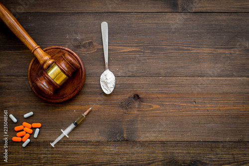 Drugs addiction, arrest for drugs. Pills, spoon with powder, syringe on dark wooden background top view space for text
