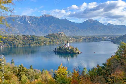 Scenic view of castle on hill (Bledski grad) and small island with church of the Assumption of Maria in center of lake Bled - the most popular hiking spot in Slovenia