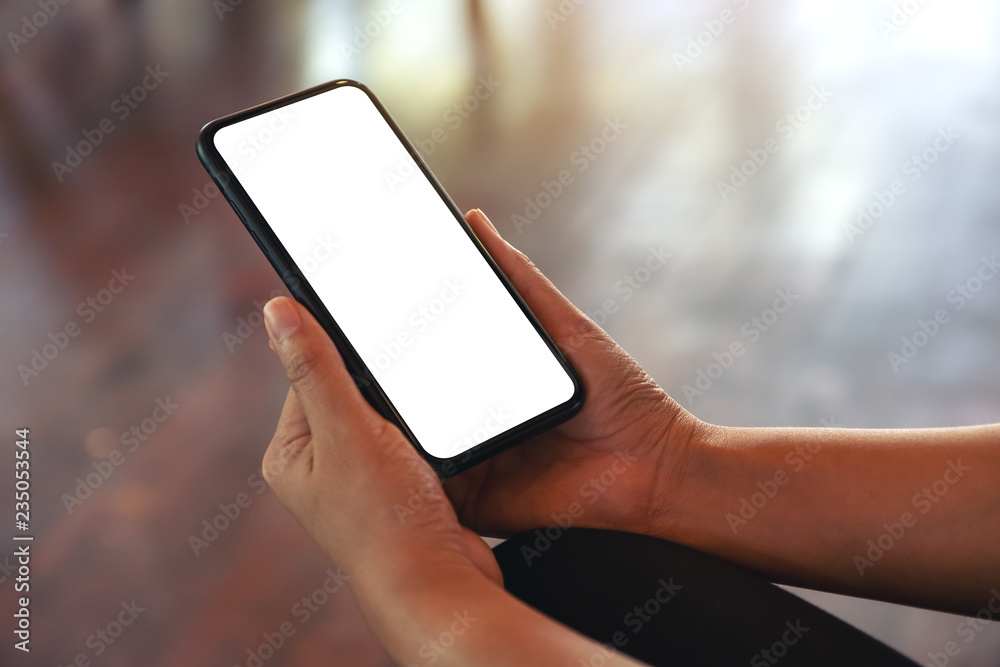 Mockup image of hands holding black mobile phone with blank white screen