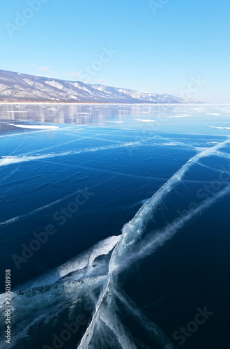 Lake Baikal in the winter. Blue smooth ice with cracks near the shore of the Small Sea Strait  Maloe More  on sunny cold February day