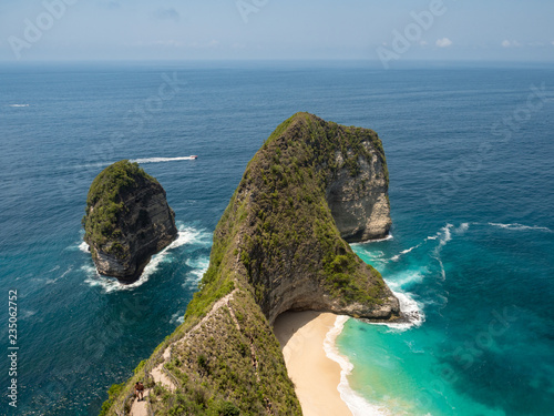 Amazing view of a Kelingking beach located in Nusa Penida, southeast of Bali Island, Indonesia. Wonderful seashore cliffs meet the great blue and turquoise ocean in a sunny blue sky. October, 2018