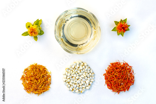 Yellow, red dried petals, inflorescences, seeds and oil of safflower against a white background. View from above. Flat lay.