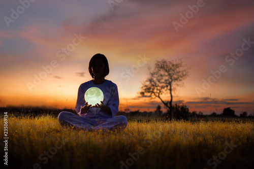 woman sitting in meditation pose with sunset background