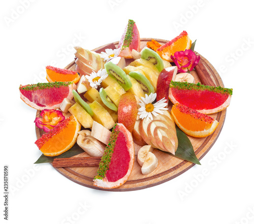 Tropical fruits assortment on a wooden plate isolated on white background photo