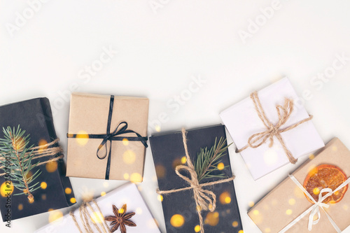 Frame from Christmas gifts in black, craft paper with rope and decorations on white background with garland lights. New Year, greetind card concept. Flat lay, top view, copy space, layout design photo