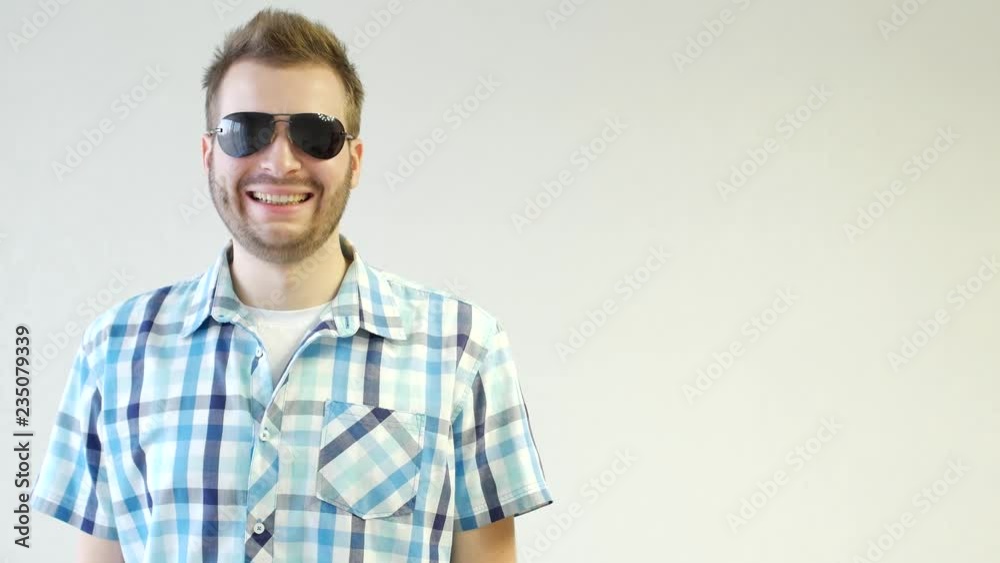 Young stylish unshaven caucasian man in black glasses is standing smiling and looking at the camera, close-up, white background, copy space, fashionable Young stylish unshaven caucasian man in black glasses is standing smiling and looking at the camera, close-up, white background, copy space, fashionable