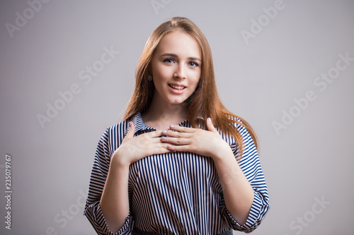 Pleasantly surprised young woman with open mouth looks away on grey background with copi space. Good news, gifts, discount photo