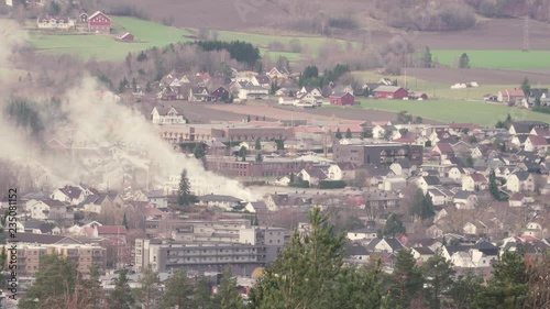 A fire is burning in the center of the town of Mj√∏ndalen in Norway.  Shot from high ground. Lots of smoke is visible. photo