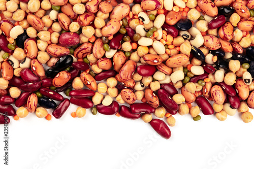 A mix of various types of legumes, shot from above on a white background with a place for text. Red kidney and pinto beans, lentils, chickpeas, soybeans and black-eyed peas. An abstract pulses texture
