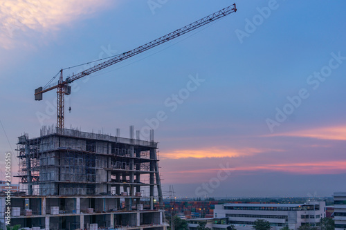 Construction of buildings with construction cranes at sunset.