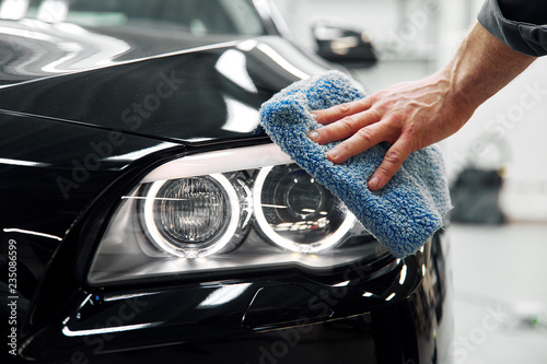 Car detailing - the man holds the microfiber in hand and polishes the car