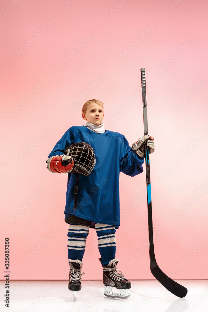 A hockey player in uniform with equipment over pink studio background. The athlete, child, sport, action concept A hockey player in uniform with equipment over pink studio background. The athlete, child, sport, action concept