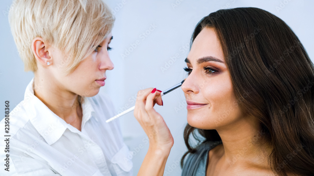 beauty salon specialist doing professional makeup for young brunette woman. people, cosmetics, lifestyle, concept beauty salon specialist doing professional makeup for young brunette woman. people, cosmetics, lifestyle, concept