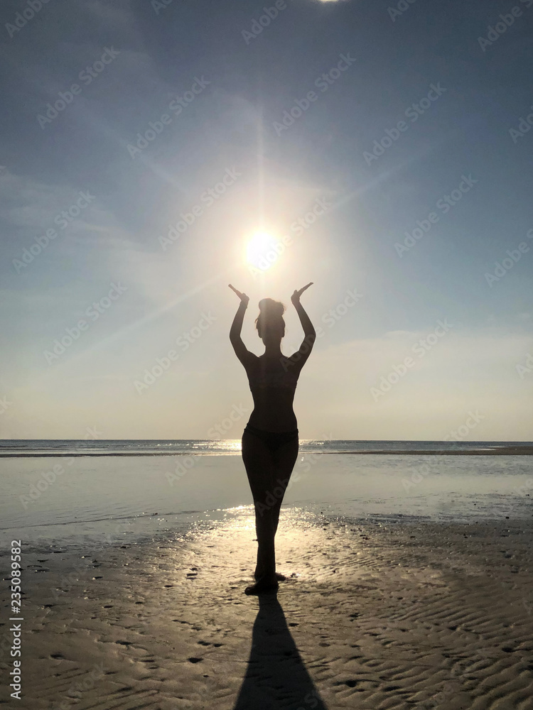 silhouette of woman at the seaside supporting the sun with her hands