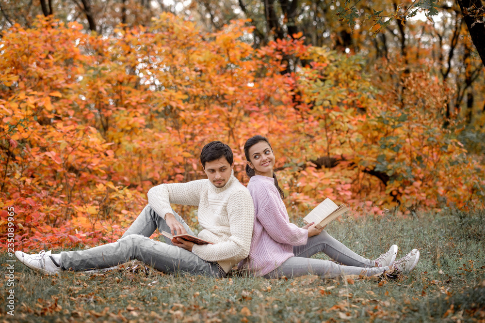 couple in love sitting in autumn park and reading book couple in love sitting in autumn park and reading book