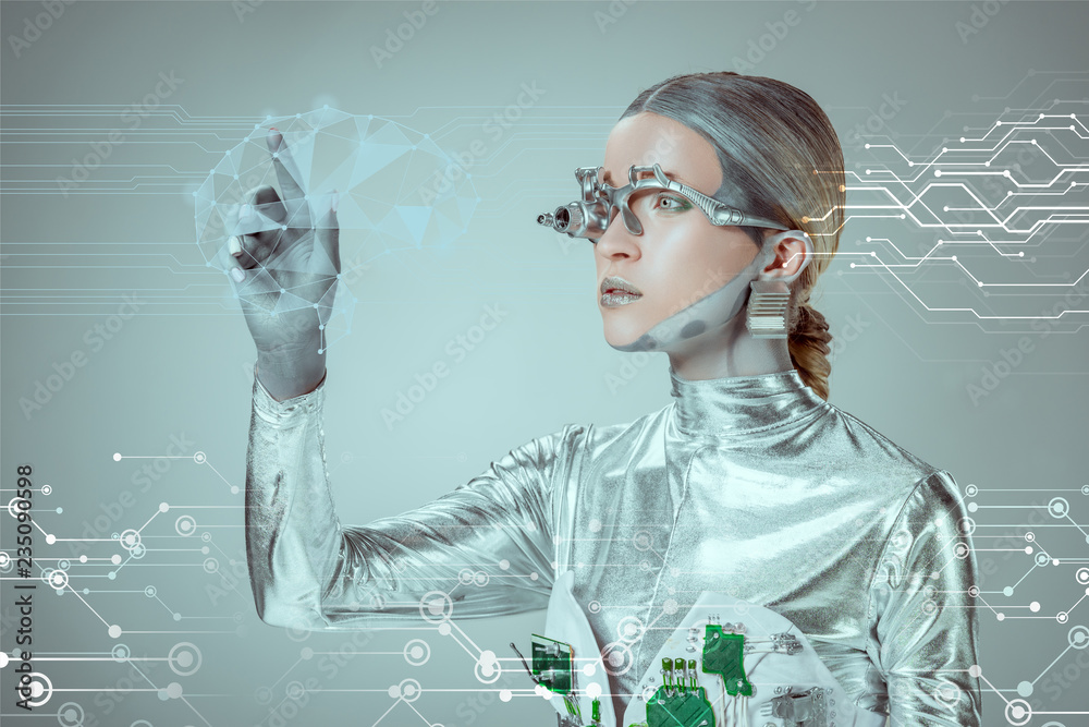 futuristic silver cyborg gesturing with hand and looking at digital data isolated on grey, future technology concept