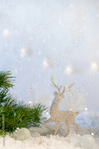 Christmas decoration on abstract twinkling lights background  soft focus. Silver deer on the snow against a background of blurry lights. Copy space for text.