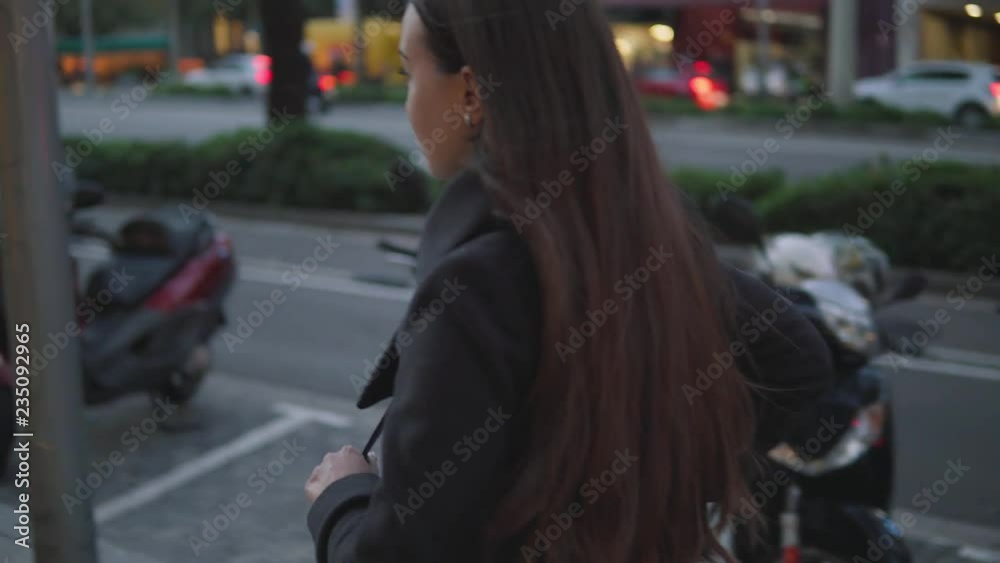 young fashionable businesswoman stands up from bench in the city square and start to walk. Traffic on background young fashionable businesswoman stands up from bench in the city square and start to walk. Traffic on background