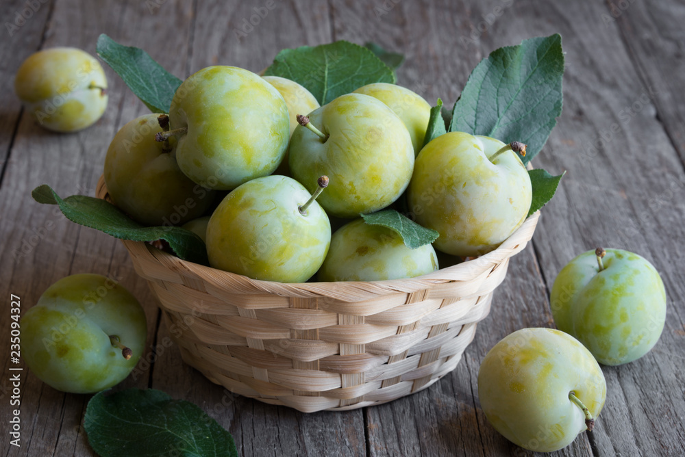 Fresh green plums in a basket on wooden background Fresh green plums in a basket on wooden background