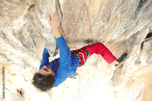 Man reaching for a grip while he rock climbs.