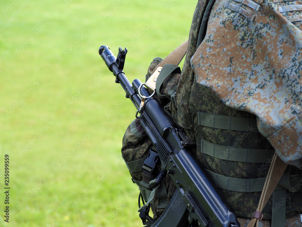 Shooting weapon, special operations forces combat. Army soldier with assault rifles and in bulletproof vests are on natural green military background Shooting weapon, special operations forces combat. Army soldier with assault rifles and in bulletproof vests are on natural green military background