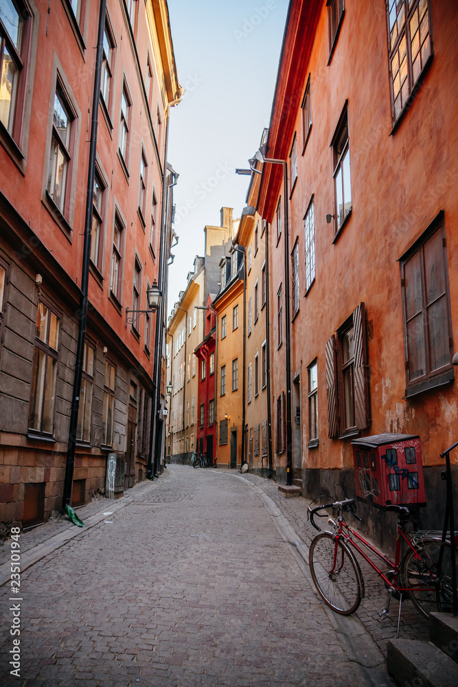 Gamla Stan. Stockholm, Sweden. Colorful street in Old Town. Color street with cobblestone road, orange houses, streetlight and bicycle. Perspective of the Narrow street.