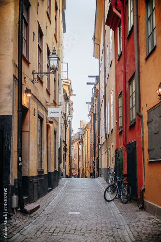 Gamla Stan. Stockholm, Sweden. Colorful street in Old Town. Color street with cobblestone road, orange houses, streetlight and bicycle. Perspective of the Narrow street.