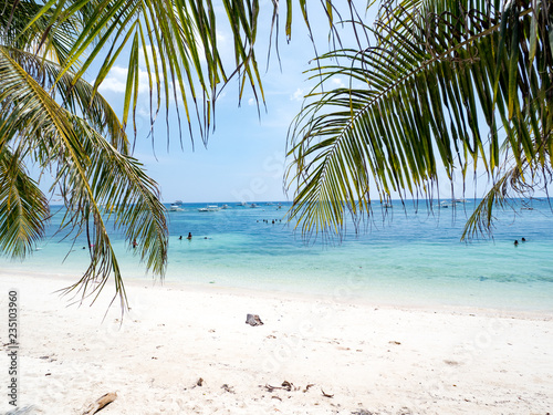 Amazing tropical beach background from Alona Beach at Panglao Bohol island, white sand beach with cloudy blue sky and palm trees. Philippines, november 2018